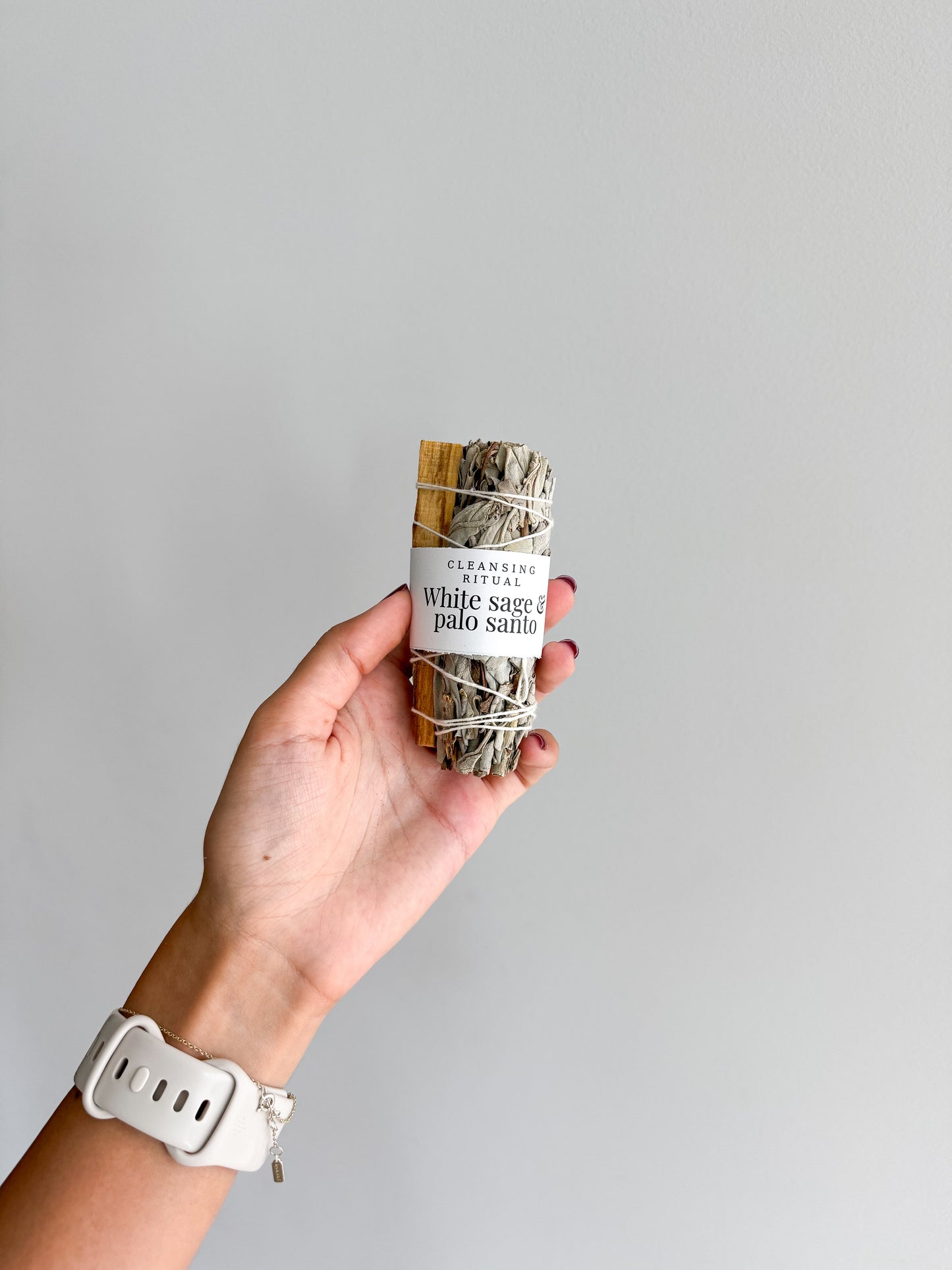 Hand holding white sage and palo santo smudge